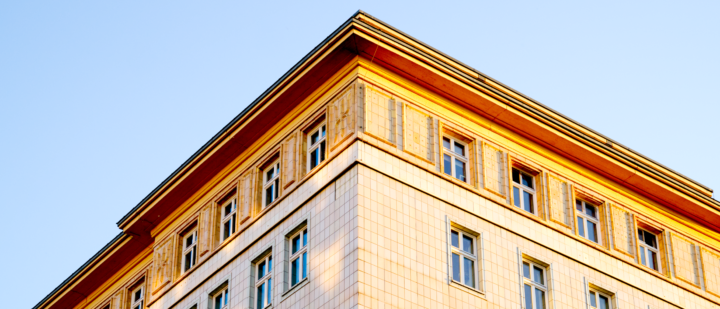 Ein symmetrisches Bild eines Hauses auf de rkarl-Marx-Allee (ehm. Stalin-Allee) in Berlin. Es ist in Abendlicht und zeigt eine Ecke des Hauses mit leichten Spiegelungen des Gegenüberliegenden Hauses.