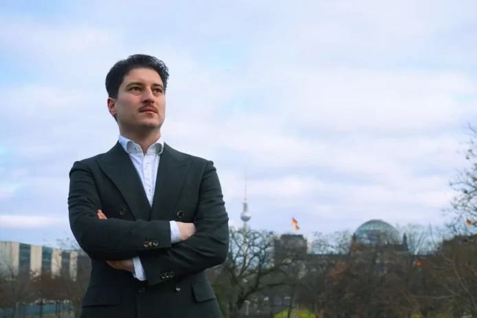 Patrick Pehl schaut entschlossen nach vorn im Hintergrund Parlament und Bundeskanzleramt