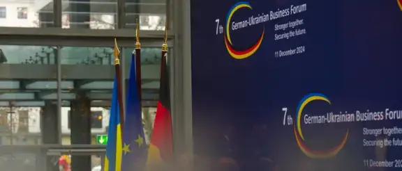 7. Deutsch-Ukrainisches-Wirtschaftsforum in Berlin am 11. Dezember 2024 - abgebildet sind drei Falggen (Deutschland EU, Ukraine) vor einer Stellwand