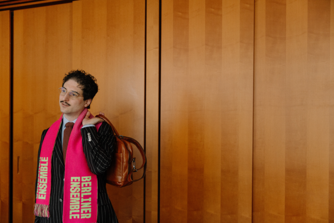 Patrick Pehl mit dem Fanschal des Berliner Ensemble vor einer holzvertäfelten Wand im Paul-Löbe-Haus (Bundestag) in Berlin.