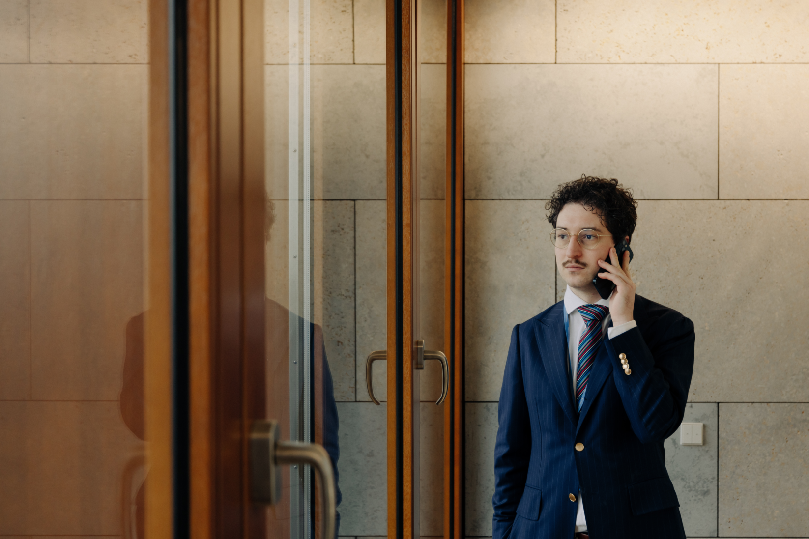 Patrick Pehl ist immer an neuer Sachpolitik interessiert und telefoniert am Fenster im Jakob-Kaiser-Haus, einer Liegenschaft des Bundestages, in Berlin. Pehl trägt einen blauen Anzug mit Nadelstreifen und eine bunt gestreifte Seidenkrawatte.