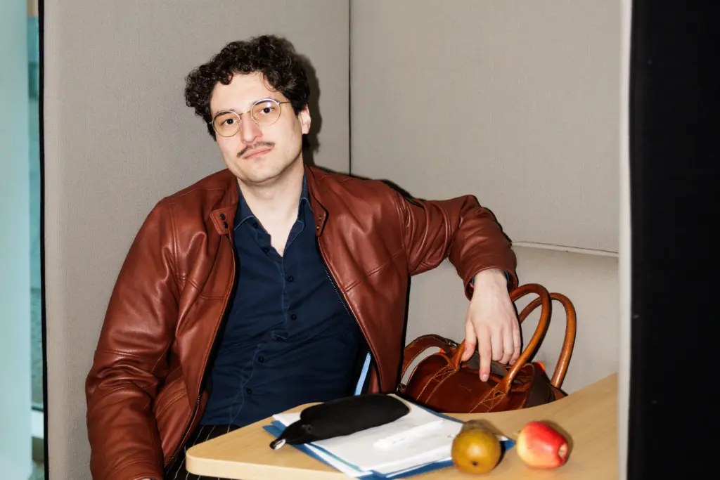 Patrick Pehl in einer braunen Lederjacke mit zwei Äpfeln und Unterlagen auf Papier im Konrad-Adenauer-Haus in Berlin.
