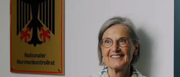 Dorothea Störr-Ritter neben dem Schild des Nationalen Normenkontrollrats in Berlin
