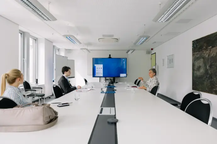 Am großen Tisch ist die Arbeit noch nicht getan. Öffentlichkeitsverantwortliche Frau Wilson achtet auf Details im Gespräch zwischen Patrick Pehl und Dorothea Störr-Ritter.