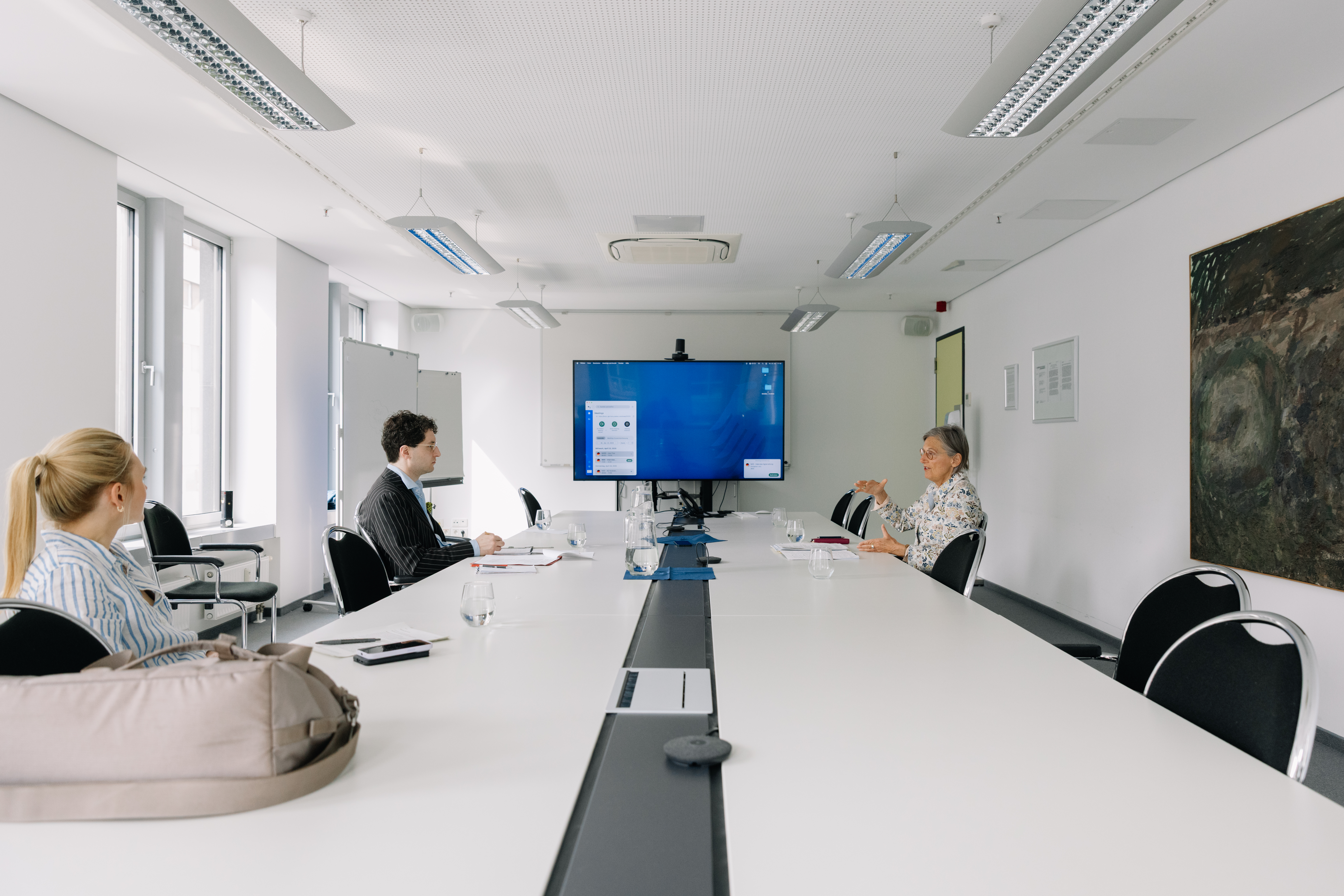 Am großen Tisch ist die Arbeit noch nicht getan. Öffentlichkeitsverantwortliche Frau Wilson achtet auf Details im Gespräch zwischen Patrick Pehl und Dorothea Störr-Ritter.