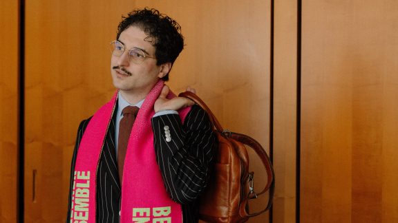 Patrick Pehl mit Fanschal des Berliner Ensemble und einer Aktentasche bei einem Interview im Bundestag